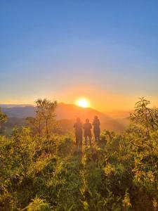 Drei Leute stehen auf einem Hügel und beobachten den Sonnenuntergang. in der Unterkunft Pousada Iasbeck in Santa Rita de Jacutinga