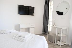ein weißes Zimmer mit einem Bett und einem Spiegel in der Unterkunft Apartments Maja in Rogoznica