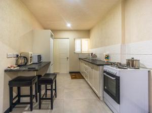 a kitchen with a stove and a counter with stools at Kahili Apartments in The Lime