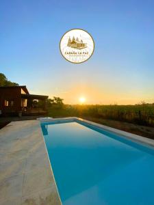 a swimming pool in front of a house with the sunset at Cabaña La Paz in San Andrés de Giles