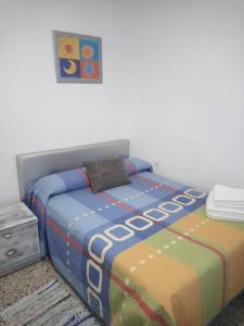1 dormitorio con 1 cama con un edredón colorido en Apartamento Tahalia 3 habitaciones, en Huelva