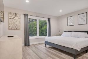 een witte slaapkamer met een bed en een raam bij Modern home near colleges in Claremont