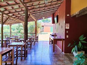 un restaurant vide avec des tables et des chaises en bois dans l'établissement Pousada Recanto do Chalé Ltda, à Macacos