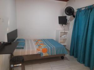 a small bedroom with a bed and a blue curtain at apartaestudios el jardin 2 in Cali