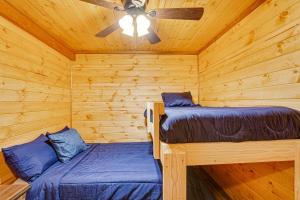 two beds in a log cabin with a ceiling fan at Cozy Quitman Fishing Cabin Near Lake Fork! in Quitman