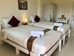 a bedroom with two beds with white sheets and red pillows at Naraya Homestay in San Pa Tong