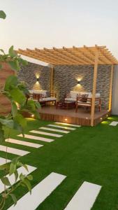 a backyard with a wooden pergola and green grass at شاليهات روشانا in Taif