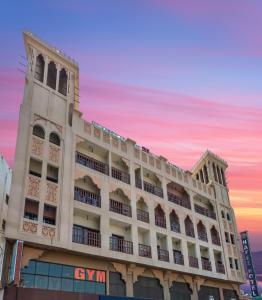 ein großes weißes Gebäude mit Sonnenuntergang im Hintergrund in der Unterkunft Hafez Hotel Apartments in Dubai