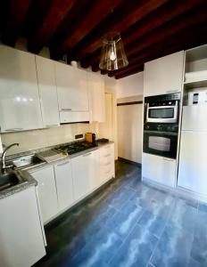 una cocina con armarios blancos y horno negro en Tiepolo 3, en Venecia