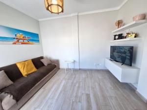 a living room with a couch and a tv at AREIAS SOL in Albufeira