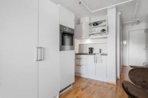 uma cozinha branca com armários brancos e um frigorífico em Budget studio by the city canal em Trondheim