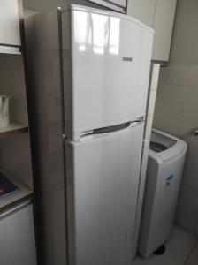 einen weißen Kühlschrank in einer Küche mit Mülleimer in der Unterkunft Apartamento inteiro no Alto Umuarama, próximo ao Aeroporto, Medicina e Granja Marileusa. in Uberlândia