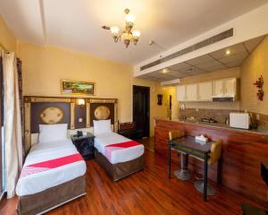 a hotel room with two beds and a kitchen at Hafez Hotel Apartments in Dubai