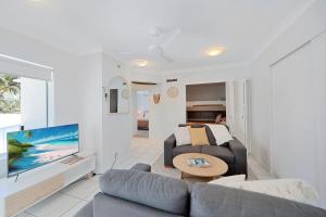 a living room with a couch and a tv at Ohana Vibe Bargara in Bargara