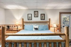 a bedroom with a large wooden bed with blue sheets at Bearadise Hot Tub 6 Min to The Island in Pigeon Forge