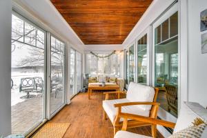 eine abgeschirmte Veranda mit weißen Möbeln und Fenstern in der Unterkunft Tranquil Auburn Lakehouse with Sunroom and Game Room! in Auburn