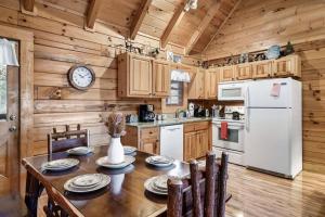 a kitchen with a table and a white refrigerator at Bearadise Hot Tub 6 Min to The Island in Pigeon Forge