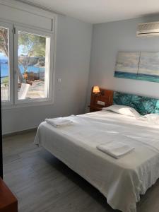una camera da letto con un grande letto bianco e una finestra di Veuràs el Mar - Almadrava Beach House a Roses