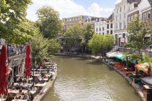 um rio com pessoas sentadas em cadeiras ao lado de um rio em Alex Place em Utrecht