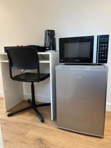 a microwave sitting on top of a desk with a chair at Novanik Studio Apartment in Milton Keynes