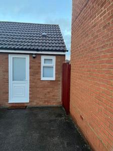 a brick house with a white door and a brick wall at Novanik Studio Apartment in Milton Keynes