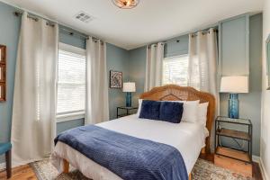 a bedroom with a bed with blue walls and windows at Chic Joplin Cottage with Patio Less Than 3 Mi to Town! in Joplin