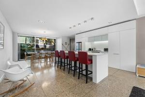 a kitchen with white cabinets and red chairs and a table at Sanctuary on Kent in Queenstown