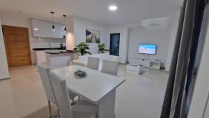 eine Küche und ein Wohnzimmer mit einem weißen Tisch und Stühlen in der Unterkunft Aparthouse EdHel T2 in Praia