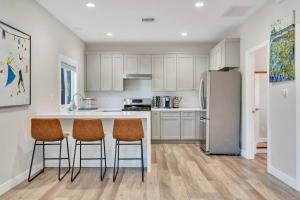 a kitchen with white cabinets and a kitchen island with bar stools at Stylish guest house near colleges in Claremont