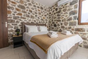 a stone walled bedroom with a bed with towels on it at Raise Polydrosos Alpine Escape in Polydrossos