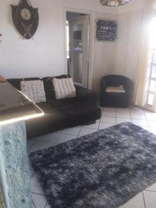 a living room with a black couch and a rug at Beleza de Angra Apartamento Aconchegante in Angra dos Reis
