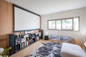 uma sala de estar com uma grande televisão de ecrã plano na parede em Splendid townhouse with private pool em Le Bouscat