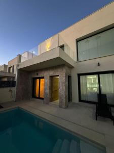 una casa con una piscina di fronte di Villa Moderna con Piscina a Daya Vieja