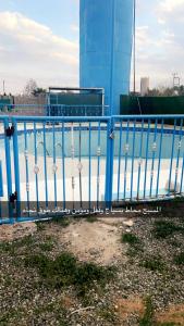 a blue metal fence next to a body of water at منتجع السرايا السياحي in Al Qā‘id