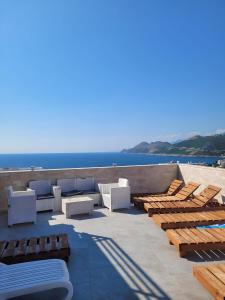 a patio with chairs and tables and the ocean at Bosfor Hotel in Dobra Voda