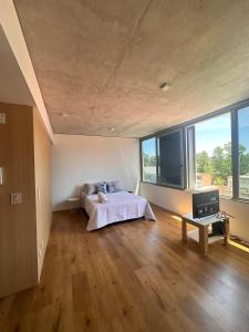 a bedroom with a bed in a room with large windows at Apartamento Dock Trade Fisherton in Rosario