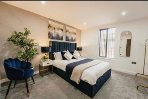 a bedroom with a large bed and a blue chair at Atlantic Suite - Wyndale Living - BHam JQ Lux 2 BR in Birmingham