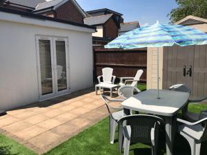 a patio with a table and chairs and an umbrella at Highcliffe Apartment with Parking in Christchurch