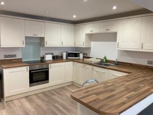 una cucina con armadi bianchi e ripiano in legno di Highcliffe Apartment with Parking a Christchurch