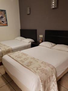 Habitación de hotel con 2 camas con sábanas blancas en Ukeinn centro en Tuxtla Gutiérrez