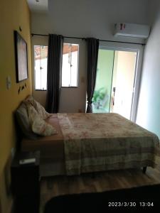 um quarto com uma cama e duas janelas em Tia Rosi tem suite independente 200mts da praia c ar e energia solar c atendimento vip em Rio das Ostras