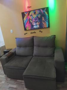 un sofá en una habitación con una pintura en la pared en Tia Rosi tem suite independente 200mts da praia c ar e energia solar c atendimento vip en Rio das Ostras