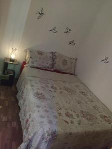 um quarto com uma cama com flores e pássaros na parede em Tia Rosi tem suite independente 200mts da praia c ar e energia solar c atendimento vip em Rio das Ostras