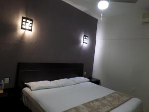 a bedroom with a bed and two lights on the wall at Ukeinn centro in Tuxtla Gutiérrez