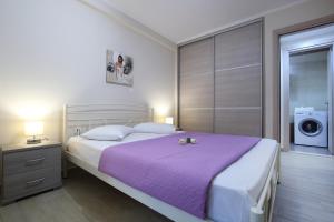 a bedroom with a large bed with a purple blanket at Neapolis Apartment in Lefkada