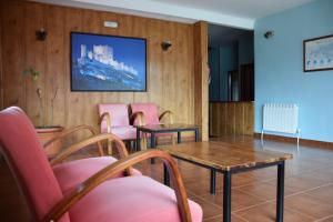 a waiting room with pink chairs and a table at Hostal Infante Peñafiel in Peñafiel