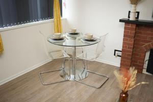 a glass table with two chairs and cups on it at Spacious Apartment - Long stays welcome in Luton