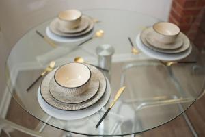 a glass table with plates and hats on it at Spacious Apartment - Long stays welcome in Luton