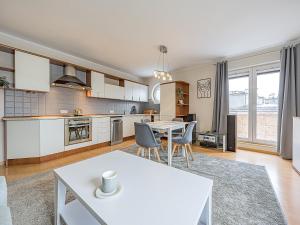 a kitchen with white cabinets and a table and chairs at CITYSTAY Reja Apartament z parkingiem in Gdynia