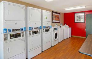 uma lavandaria com máquinas de lavar roupa brancas e uma parede vermelha em Extended Stay America Select Suites - Durham - University em Durham